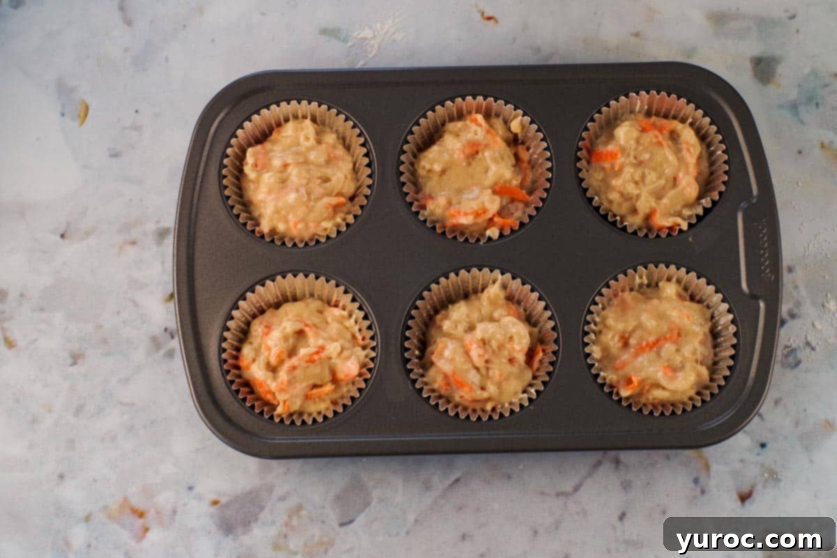 Glazed Carrot Cake Doughnut Muffins 10 Muffin tins filled approximately two-thirds full with carrot cake muffin batter.