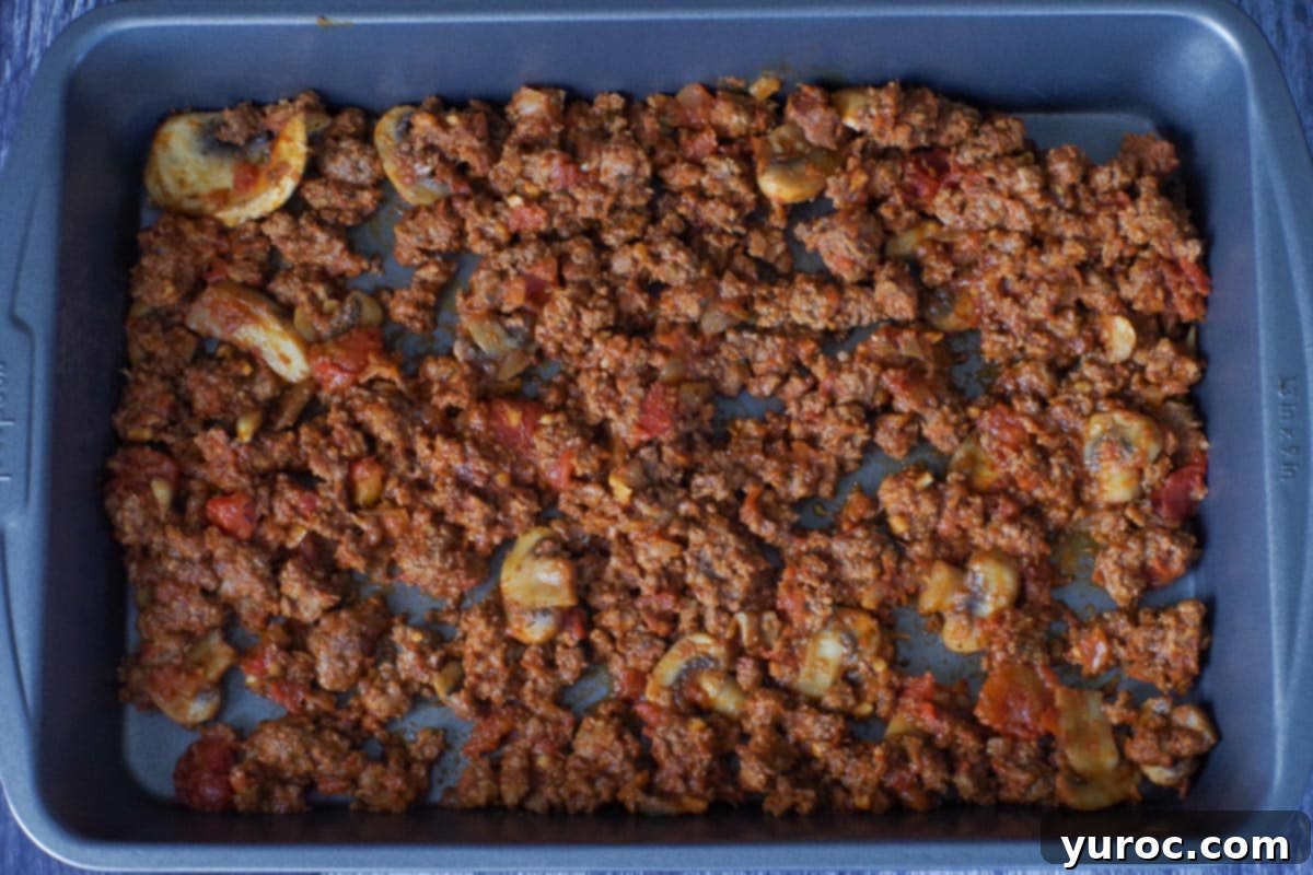 meat sauce on the bottom of a lasagna pan