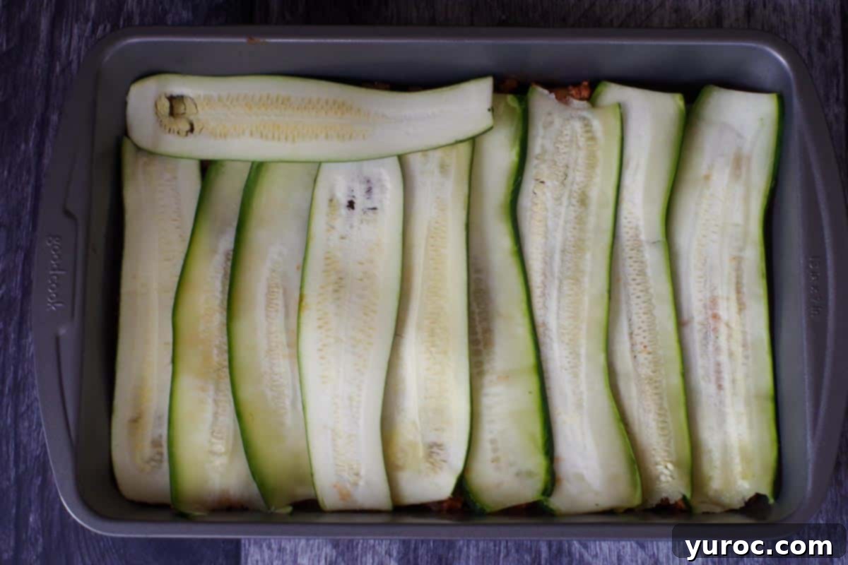 zucchini slices on top of meat layer in lasagna pan