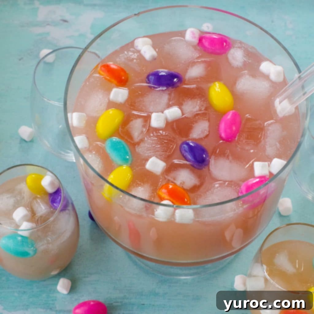 Easter punch in a trifle bowl with glasses around, as well as marshmallow Easter eggs and mini marshmallows