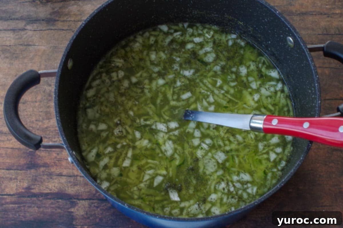 Wholesome Zucchini Potato Dill Soup 4 Chopped onion, fresh garlic, dried dill, shredded zucchini, chicken broth, and water simmering together in a large pot on the stove.