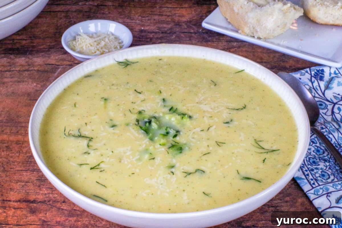 Wholesome Zucchini Potato Dill Soup 9 A beautifully garnished bowl of Zucchini Potato Soup with fresh dill, a swirl of sour cream, and a side dish of grated Parmesan cheese, ready for serving.