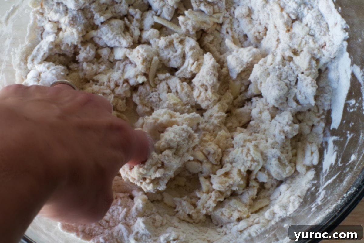 finger mixing cream into dry mixture in large glass bowl