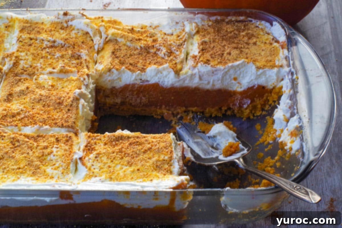 Effortless Pumpkin Perfection 14 A layered pumpkin dessert in a pan with several pieces already removed, and a pie lifter poised to serve another slice.