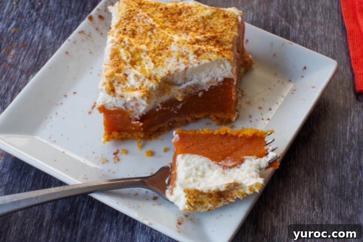 Effortless Pumpkin Perfection 16 A perfectly portioned slice of layered pumpkin dessert on a white plate, with a fork cutting into it, ready to be enjoyed.