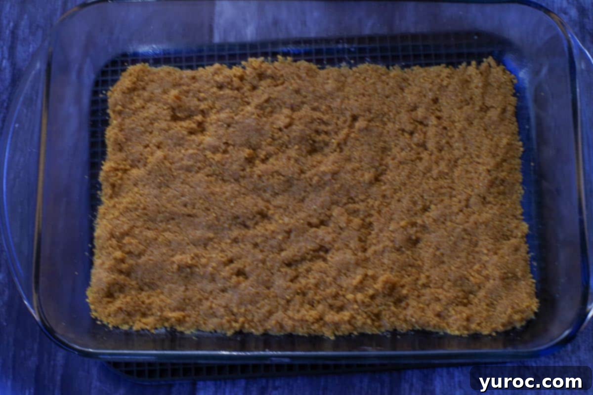 Effortless Pumpkin Perfection 5 The graham cracker crumb mixture pressed firmly and evenly into the bottom of a glass baking pan.