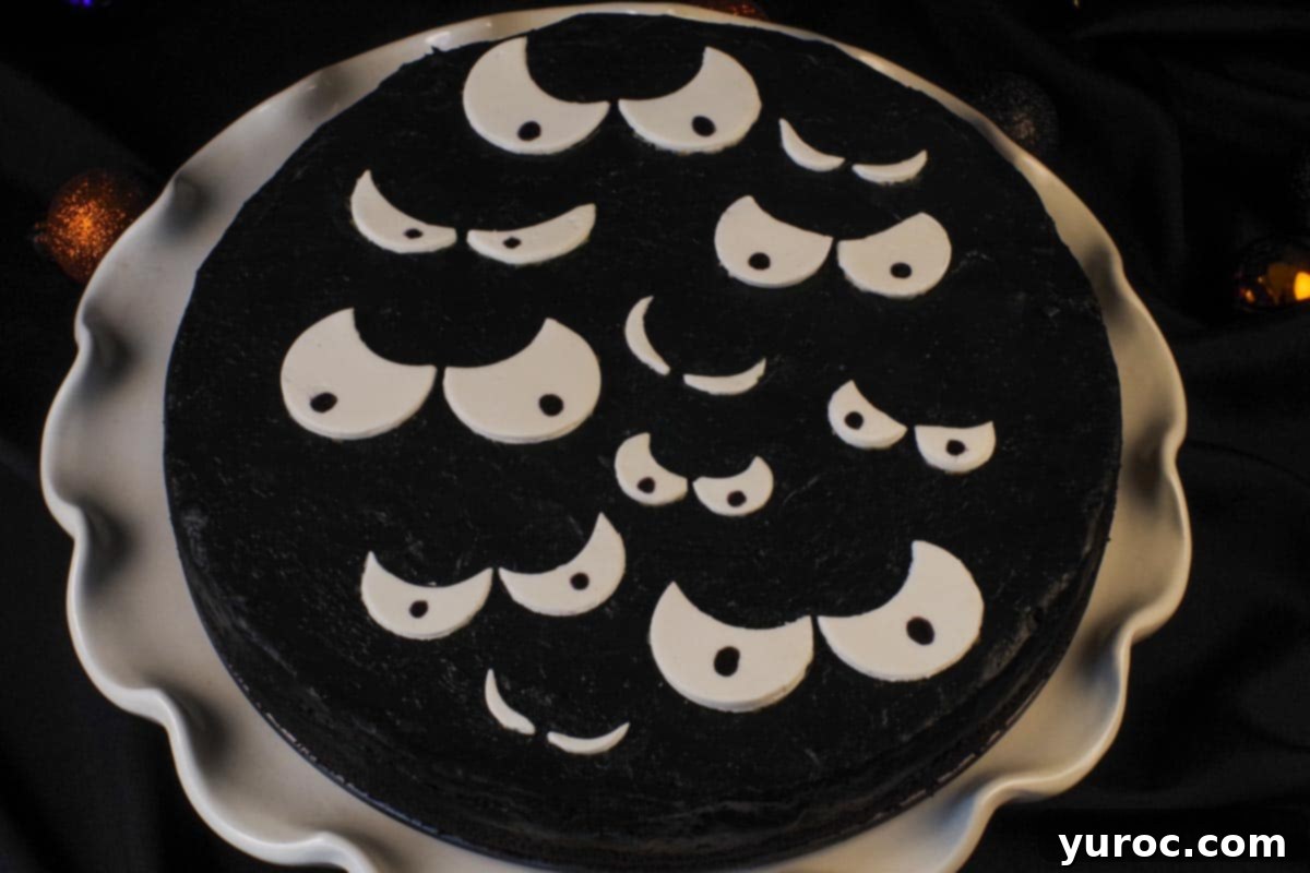 black cheesecake with white scary eyes on white cake stand