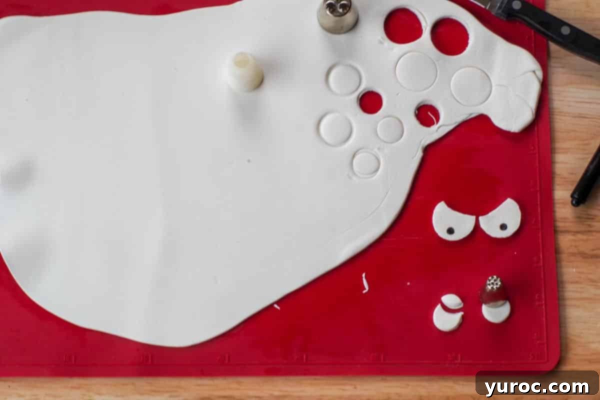 eyeballs being cut out of the fondant with the round end of piping tips and eyeballs drawn with edible black marker