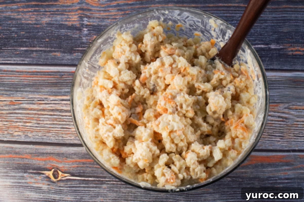 onion and butter mixed into other ingredients in a large glass bowl with dark wooden spoon