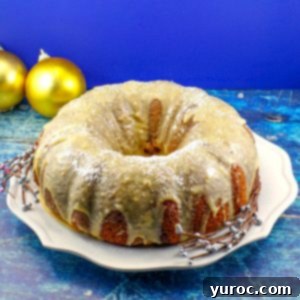 Whole butter tart bundt cake on a white plate, elegantly surrounded by gold Christmas ornaments, showcasing its festive appeal.