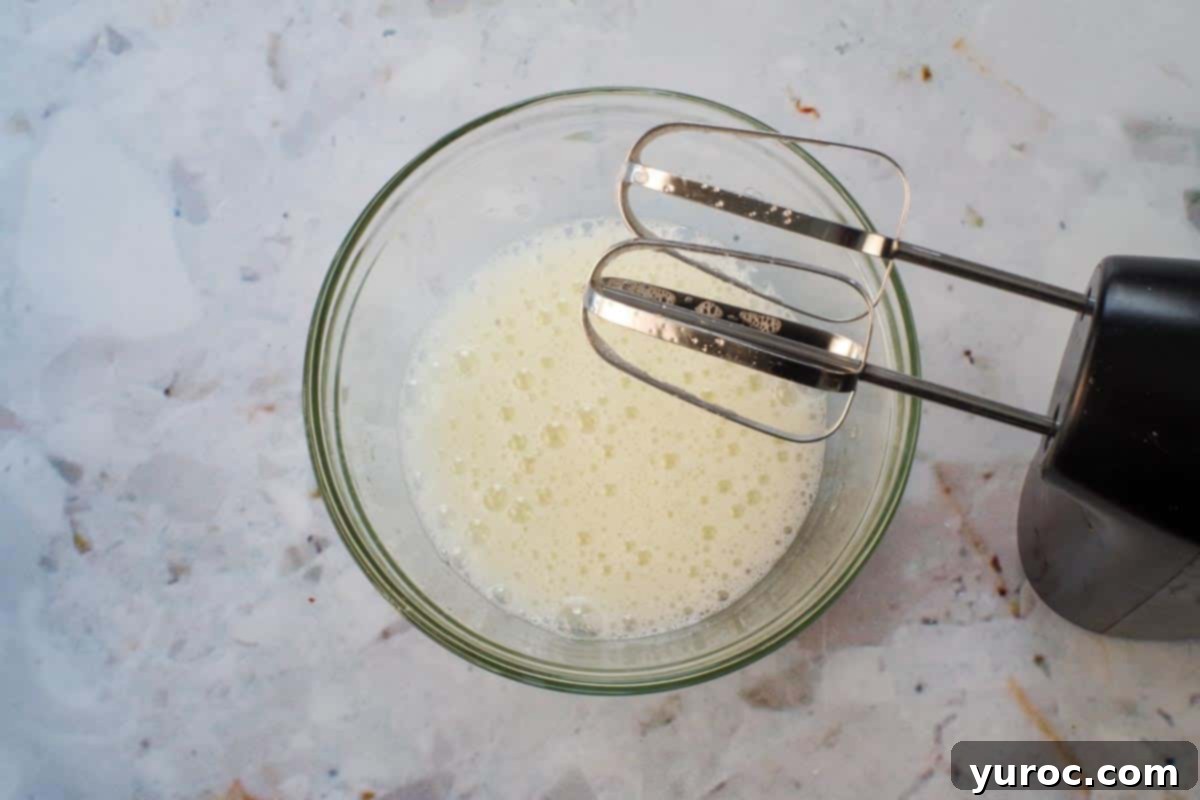 Bread Machine Ukrainian Easter Babka 12 Beaten foamy egg whites in glass bowl, with beaters over bowl.