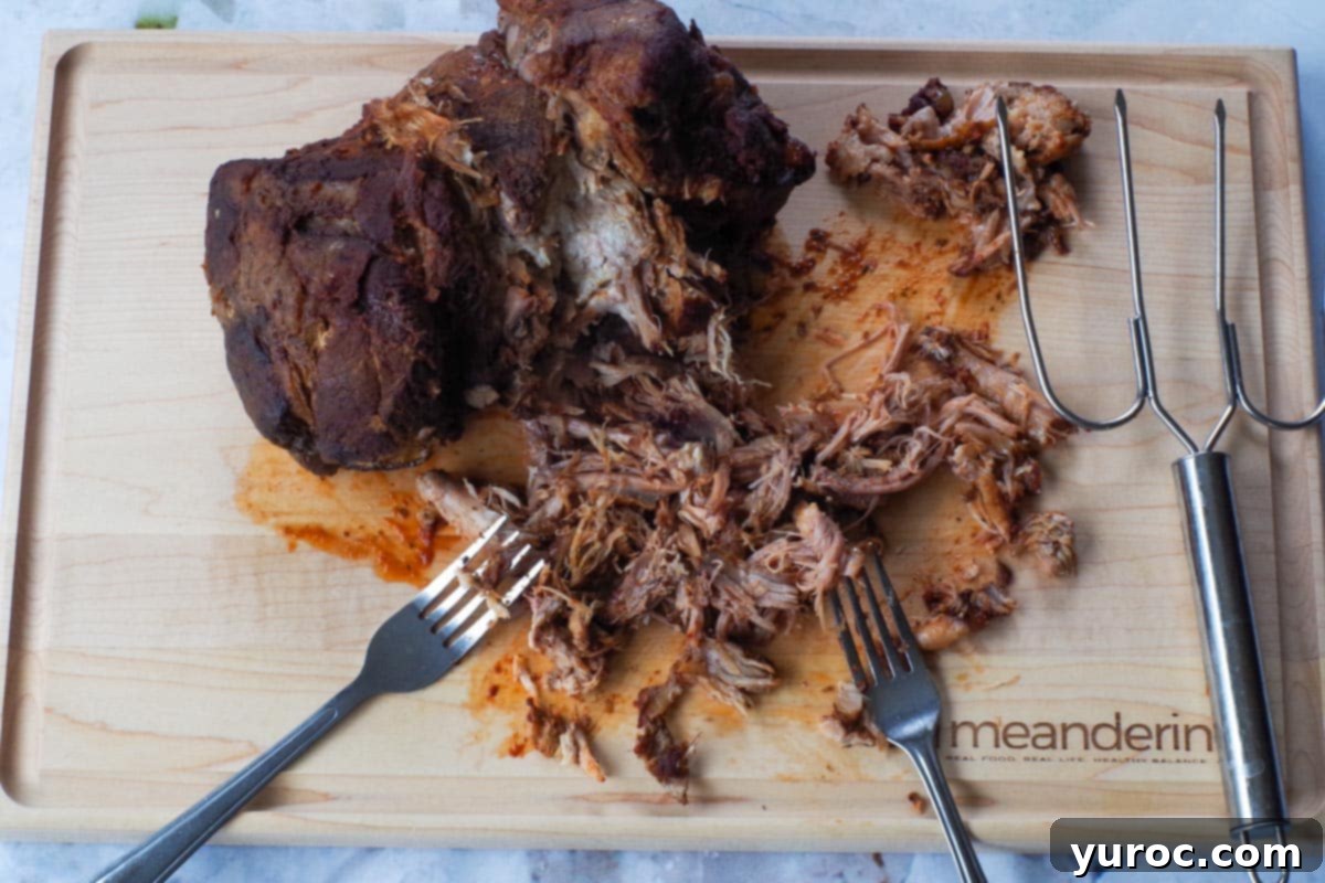 Pork being pulled/shredded with 2 forks.