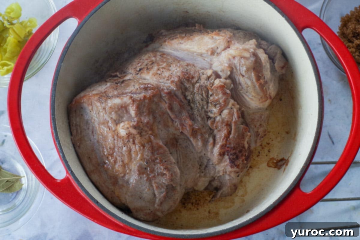 Browned pork shoulder in a Dutch oven.