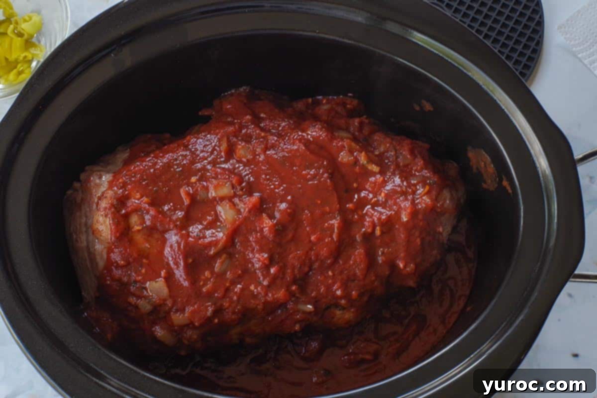 Sauce poured over pork shoulder in the slow cooker.