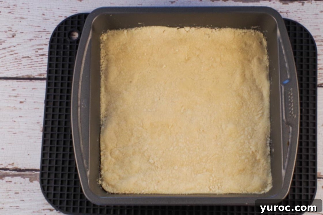 The pre-baked shortbread base resting on a large black rectangle trivet after being removed from the oven.