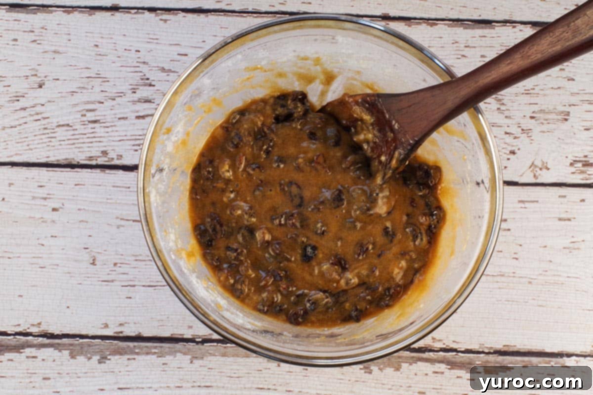 Filling ingredients mixed together in a medium glass bowl with a dark wooden spoon, showing the gooey texture.