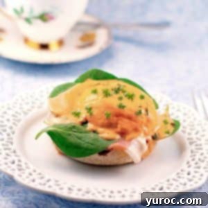 Eggs Benedict with Prosciutto on a white plate with a lattice trim with a china tea cup in background.