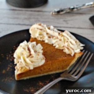 Prize-Winning Canned Pumpkin Pie 10 A perfect slice of pumpkin pie, adorned with a swirl of whipped cream, presented on a chic black plate, with a full pie on a platter in the background.