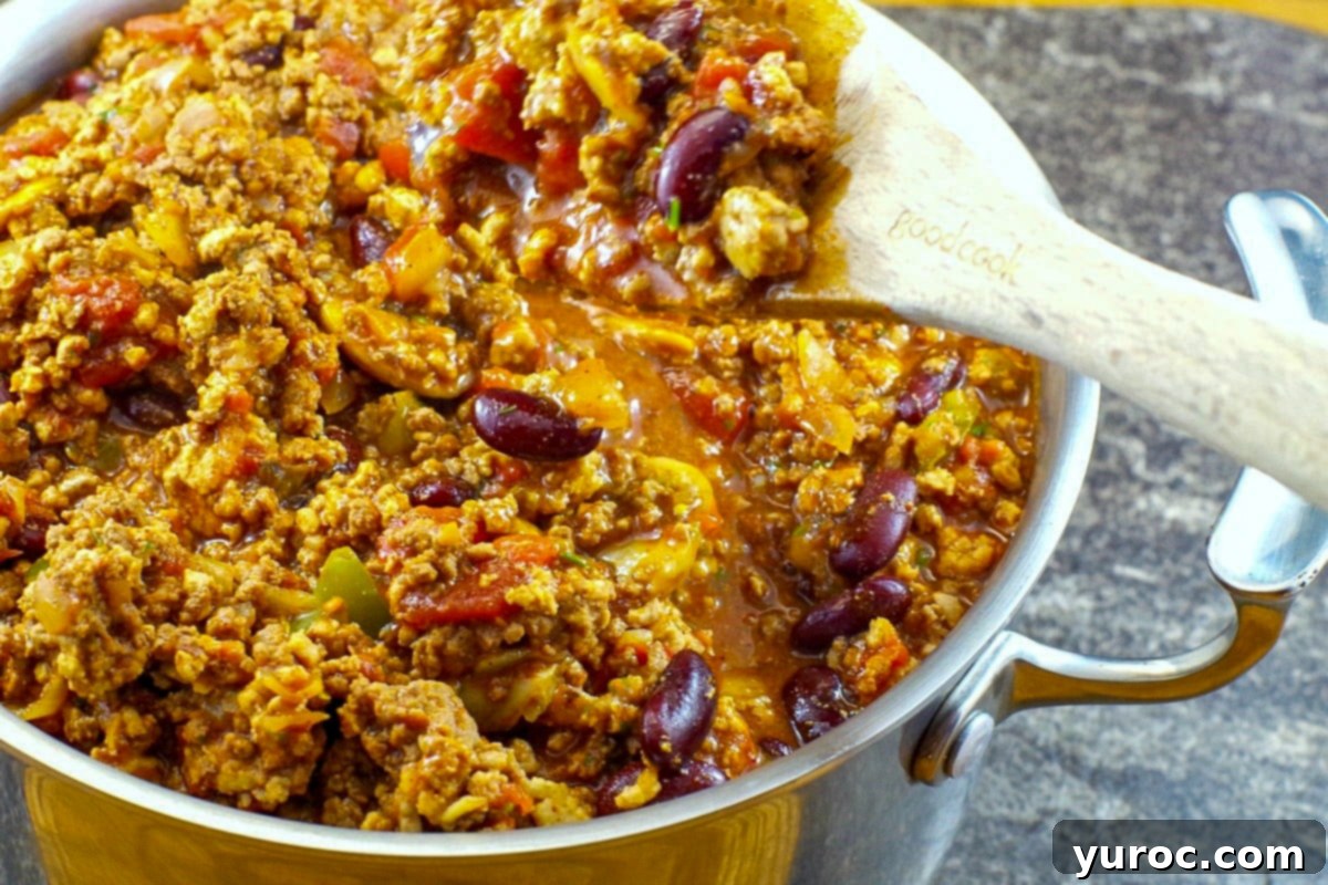 chili in a pot with a wooden spoon scooping some out