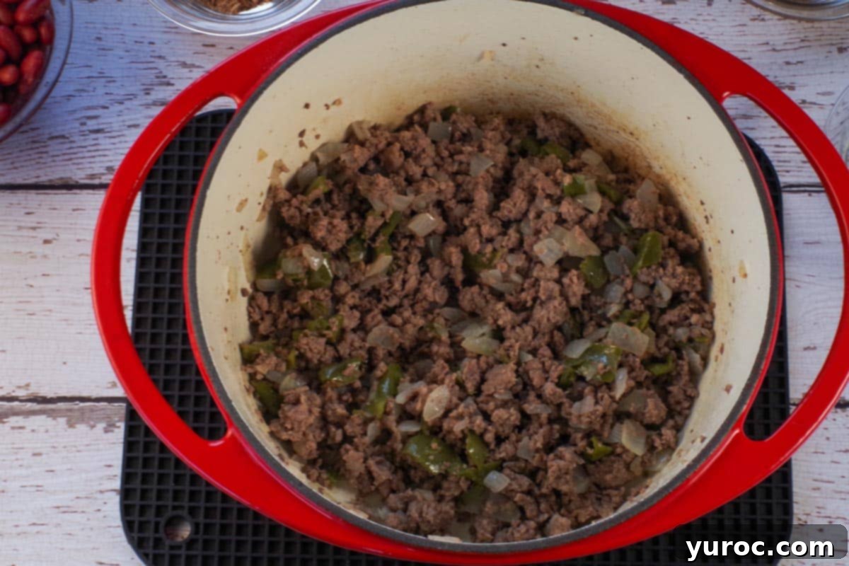 ground beef and pork with onions and green peppers browned in orange dutch oven