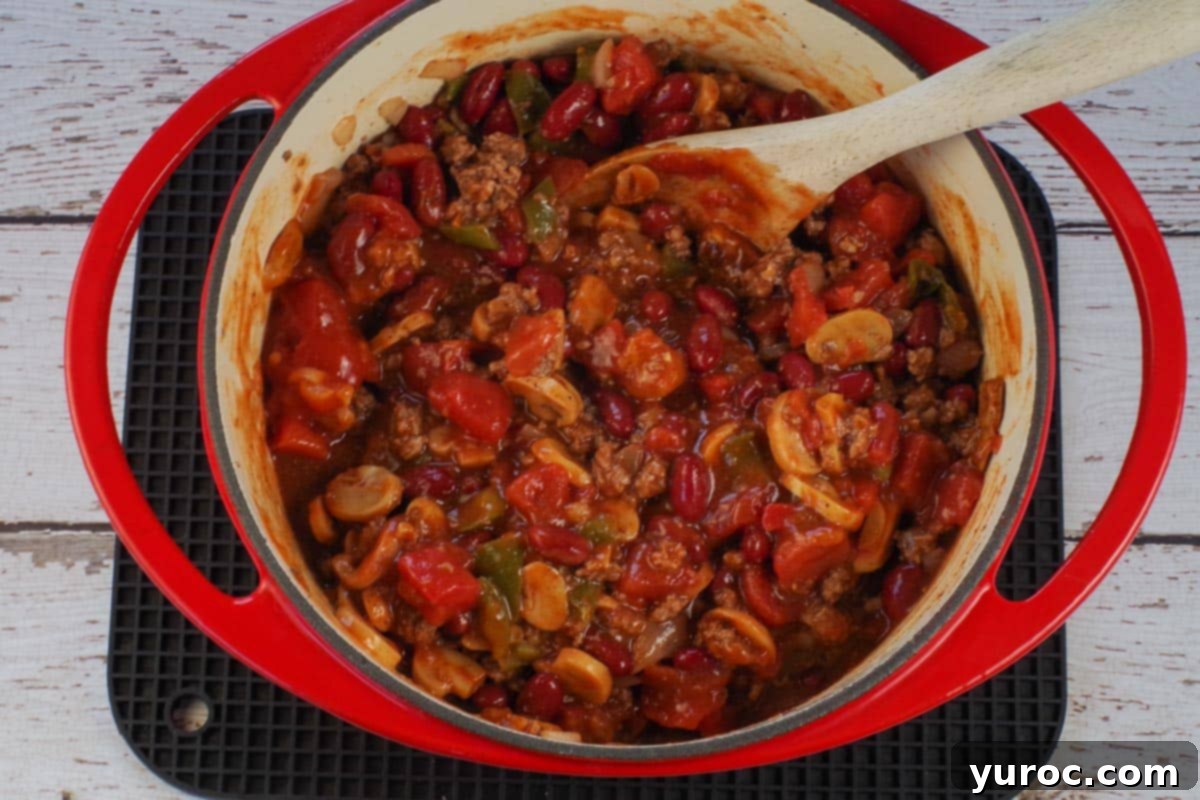 beef and pork with other chili ingredients besides dill and garnishes in orange dutch oven