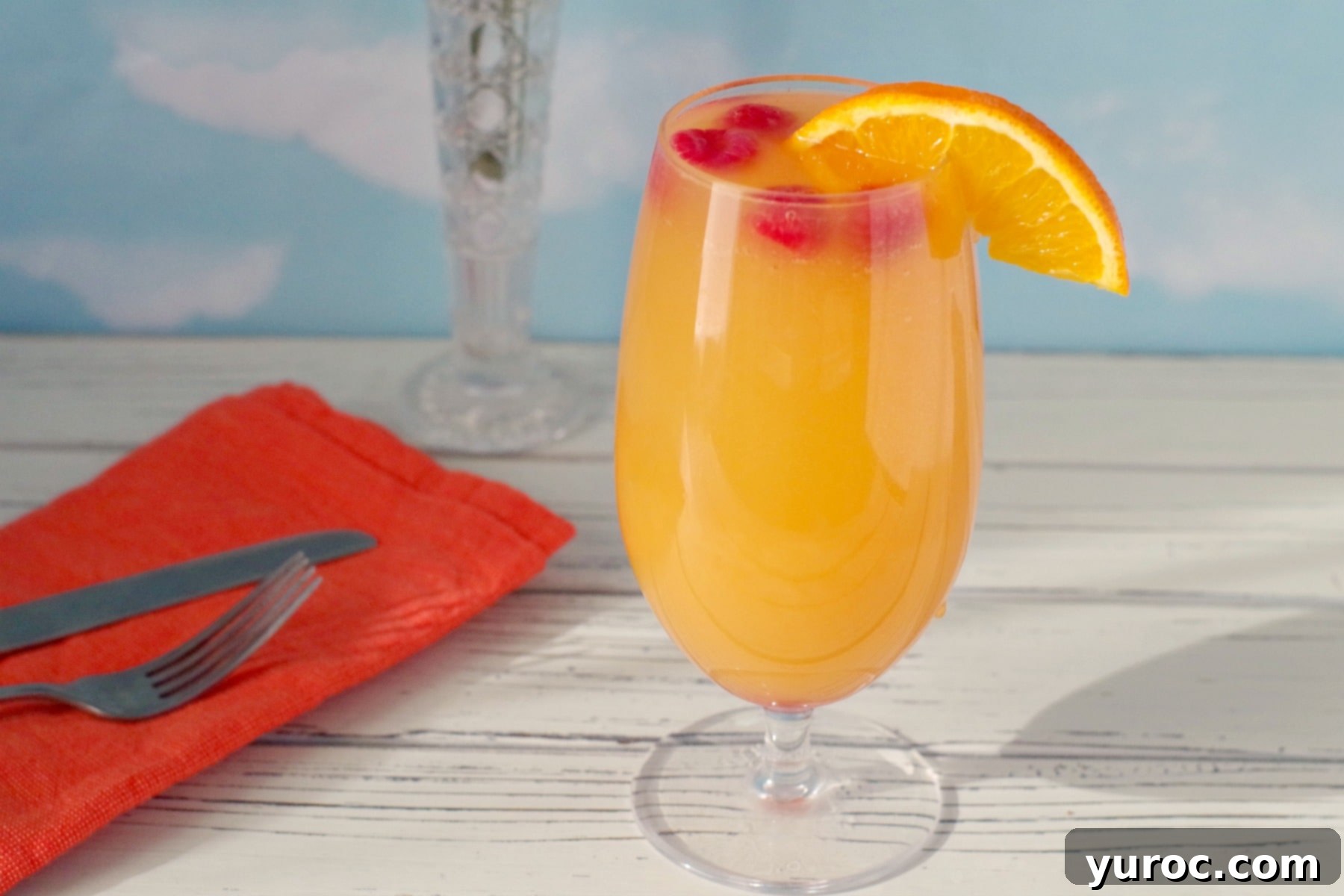 mimosa drink with raspberries and orange garnish