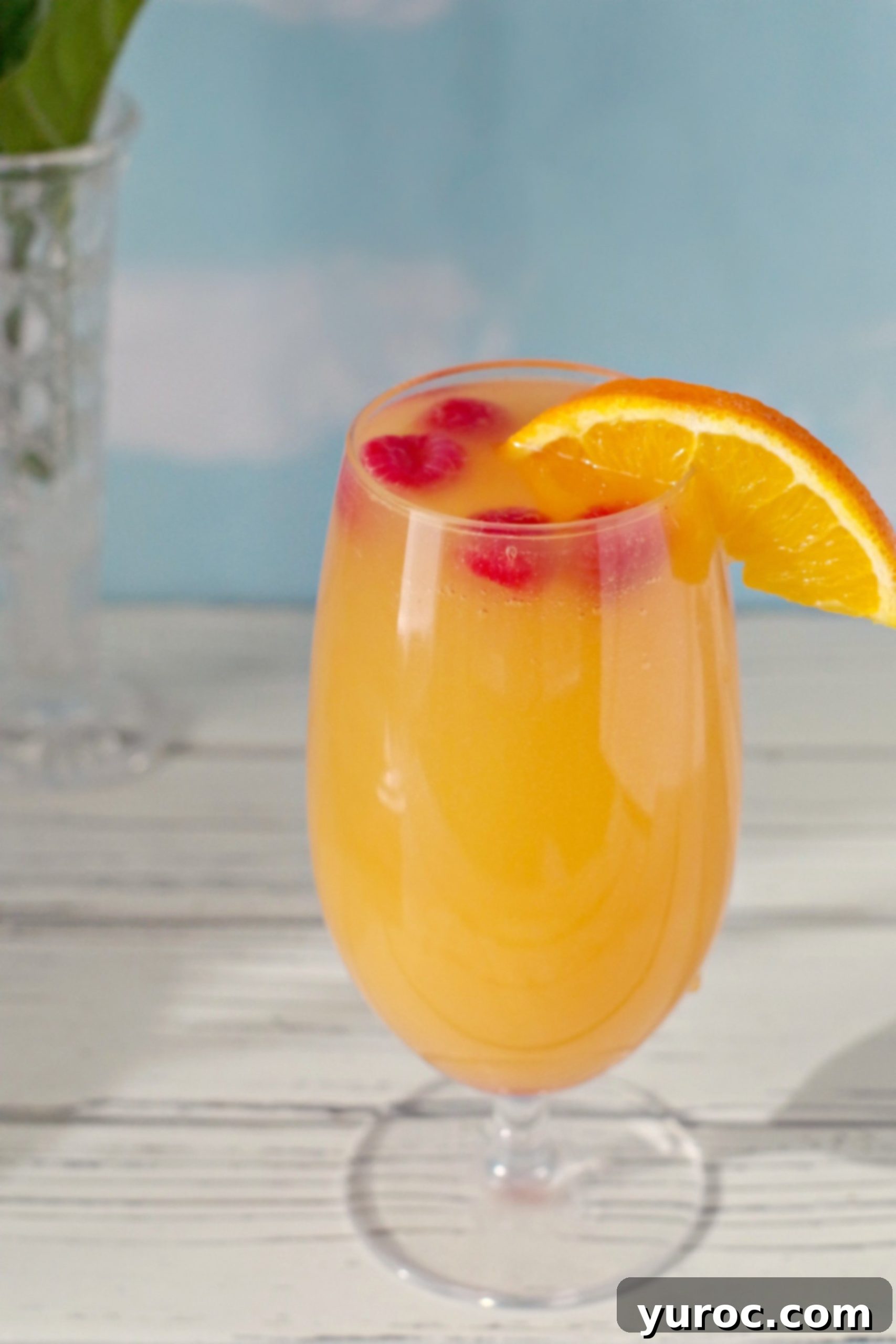 mimosa drink with raspberries and orange garnish