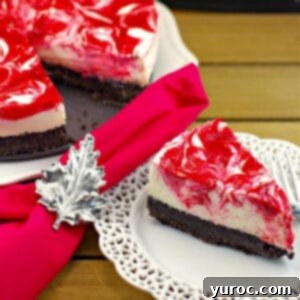 a piece of strawberry rhubarb cheesecake on a white plate with a red napkin with Canadian flag napkin ring and remainder of cake in the background