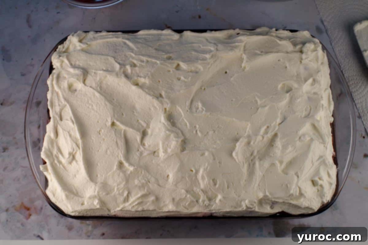Whipped cream spread over the cherry pie filling layer.