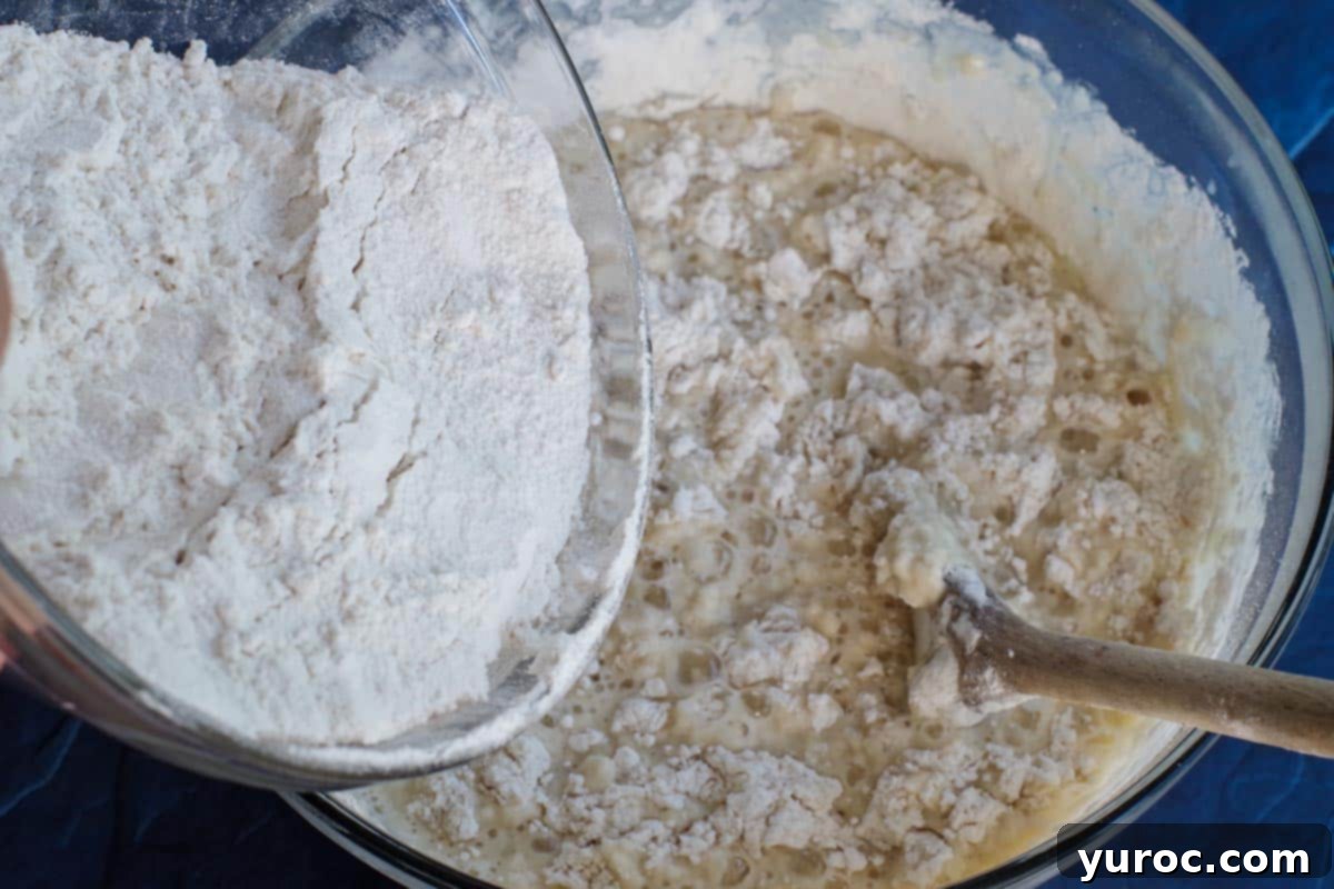 All-purpose flour gradually being incorporated into the wet dough mixture.