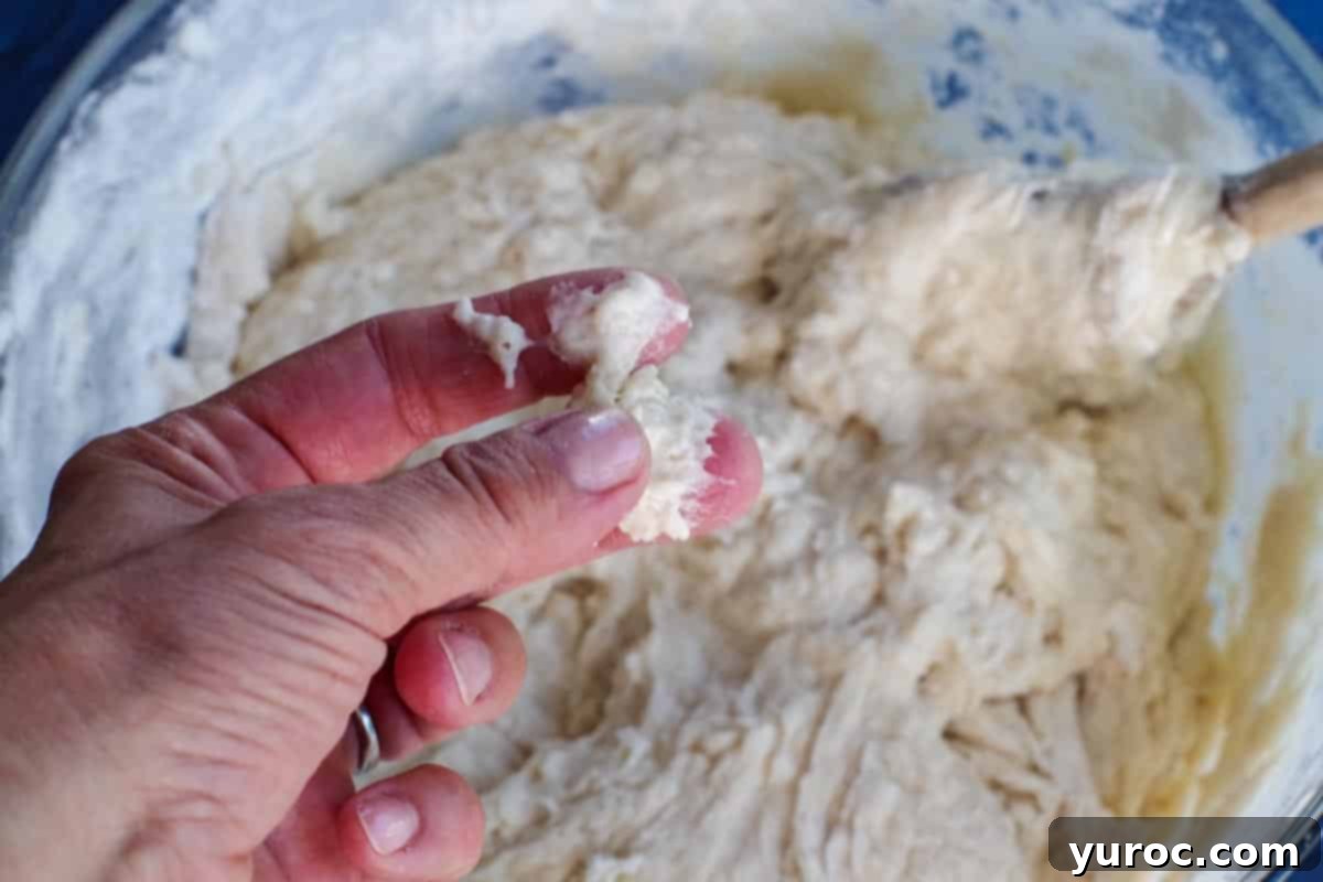 Sticky dough clinging to fingers, indicating more flour is needed.