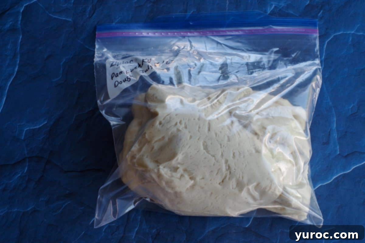 Pampushky dough stored in a labelled freezer bag on a blue surface, ready for freezing.