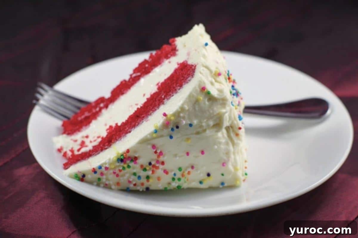 Decadent Red Velvet Ice Cream Cake 13 A perfectly sliced piece of red velvet ice cream cake on a white plate with a fork
