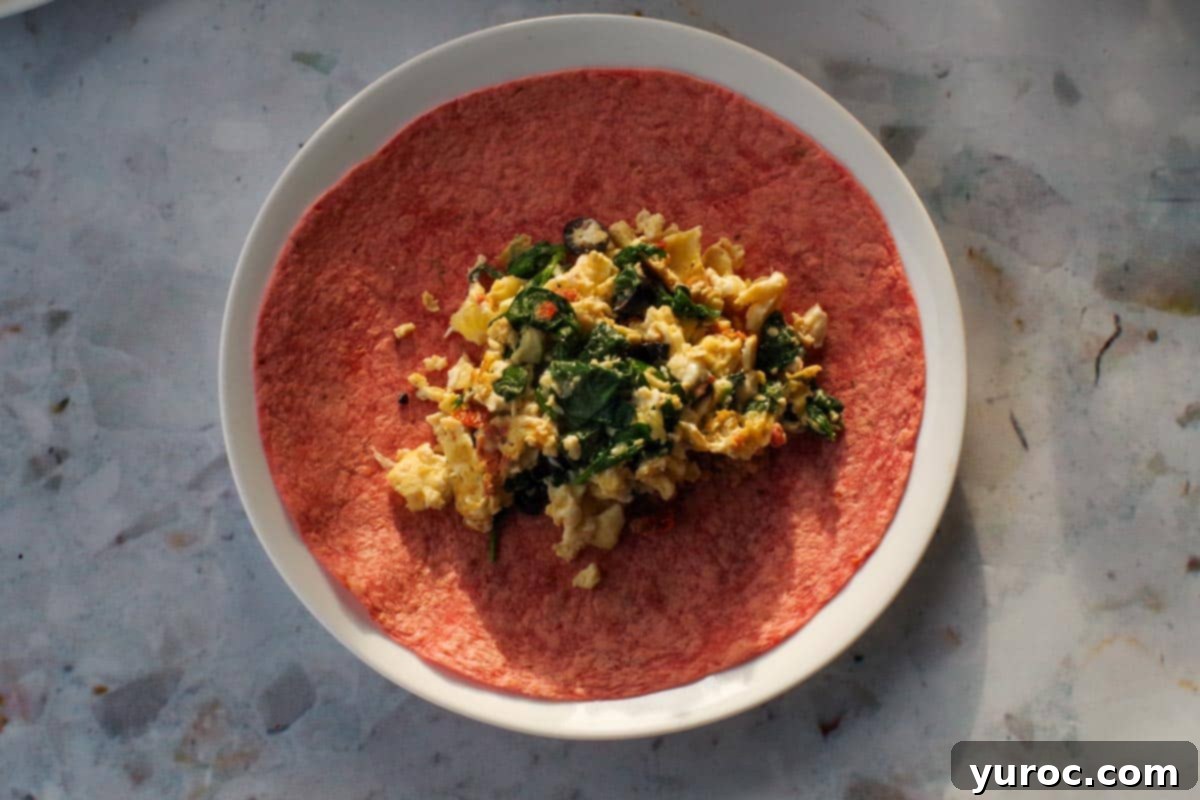 Egg mixture added on top of refried beans on tortilla.