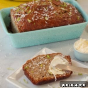Tropical banana bread in blue loaf pan with slice of banana bread on a white plate with butter