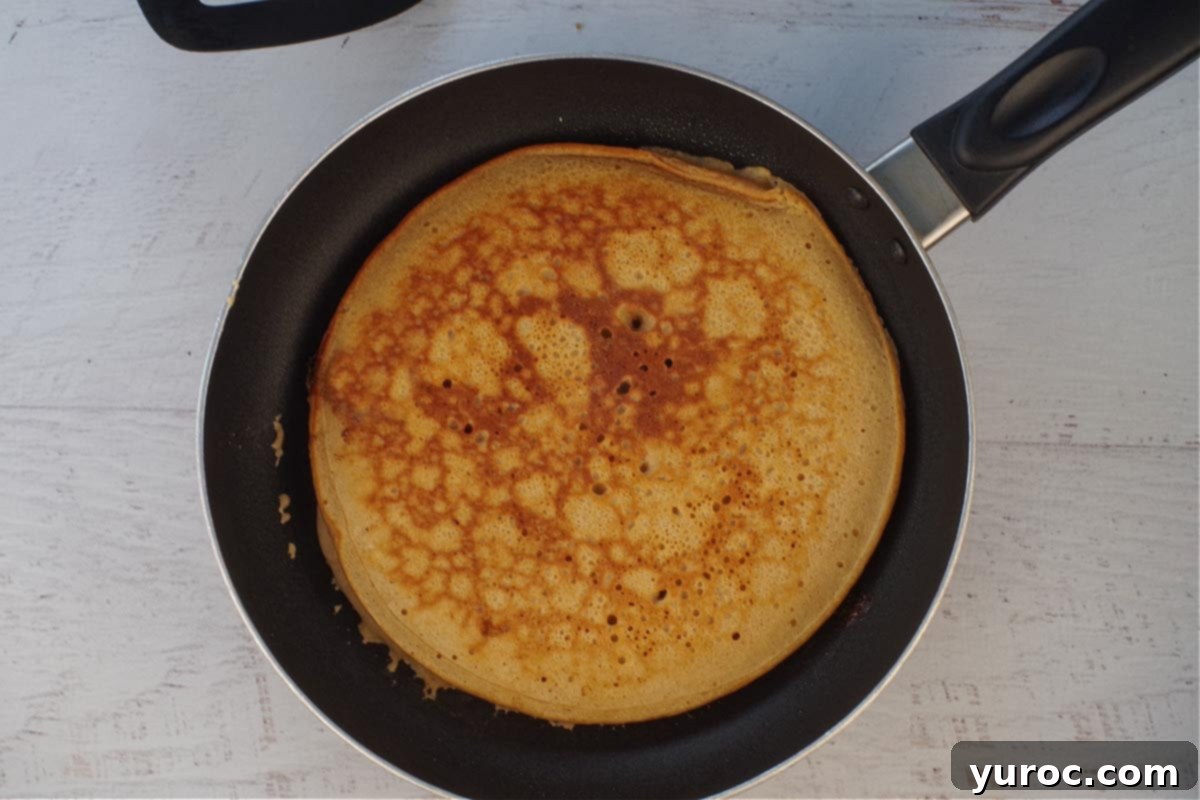 Holiday Spiced Gingerbread Pancakes with Sweet-Tart Cranberry Compote 14 A perfectly cooked gingerbread Christmas pancake, golden brown on both sides, resting in a frying pan.