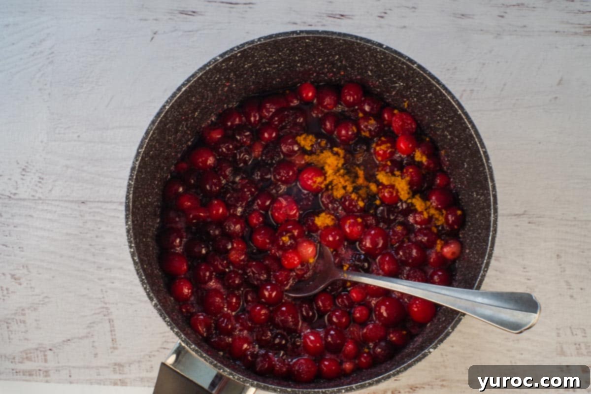 Holiday Spiced Gingerbread Pancakes with Sweet-Tart Cranberry Compote 6 Cranberry compote simmering gently in a pot, with orange zest and vanilla added, becoming syrupy.