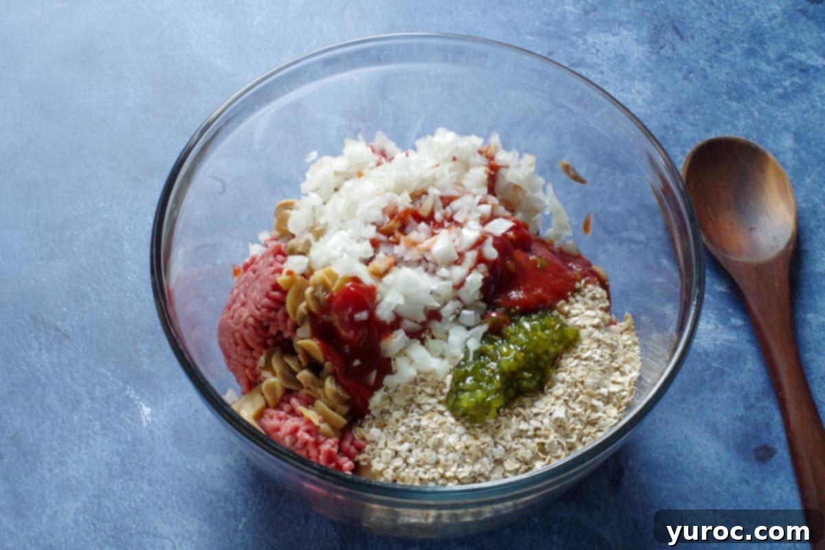 meatloaf ingredients in a large glass mixing bowl, with a wooden spoon on the side