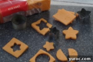 cheese cut outs with mini cookie cutters on a grey cutting board