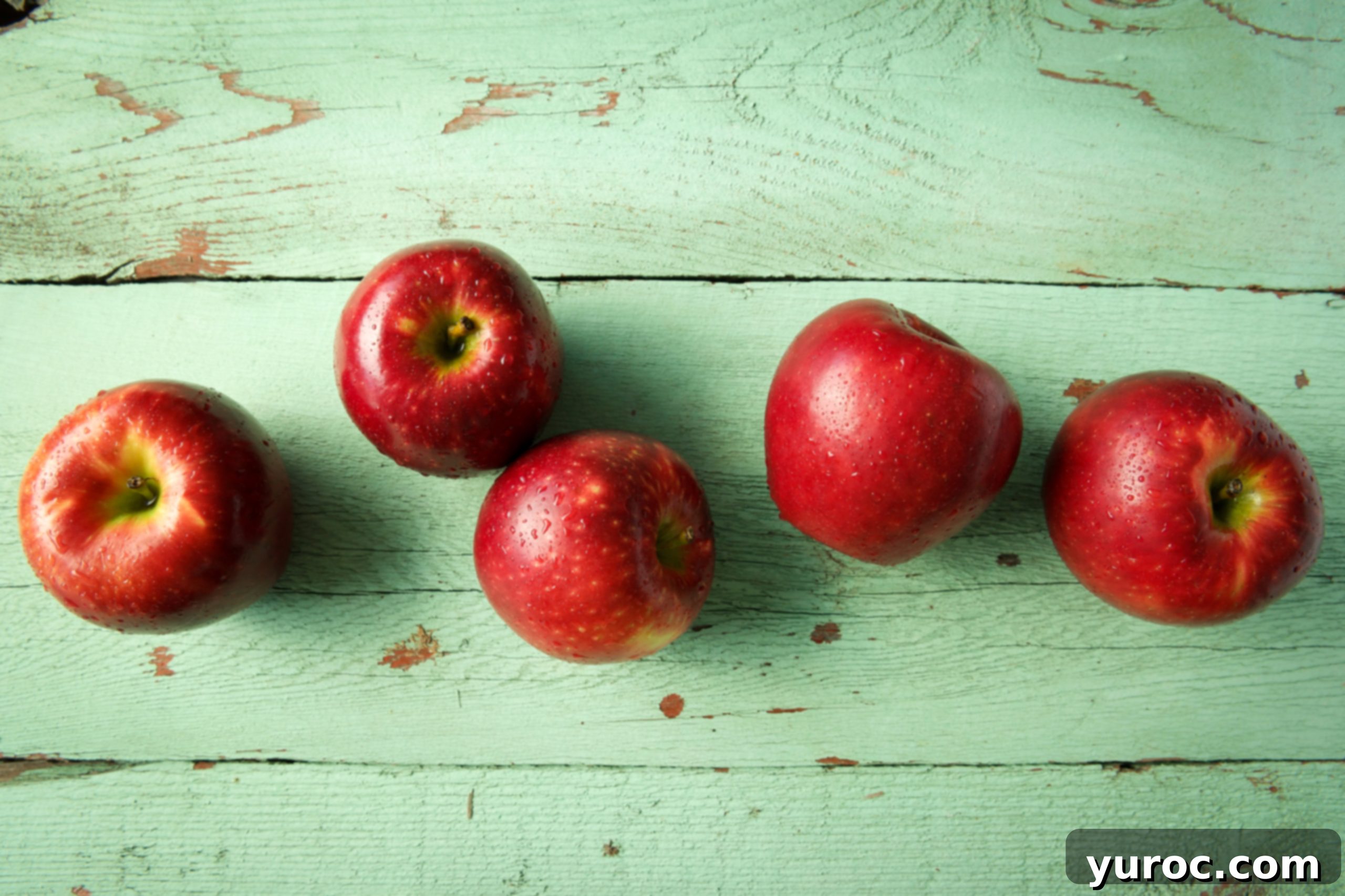 5 Cosmic Crisp apples on a green wooden background