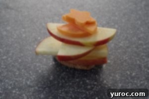 cheese shapes added to apple slices on a grey cutting board