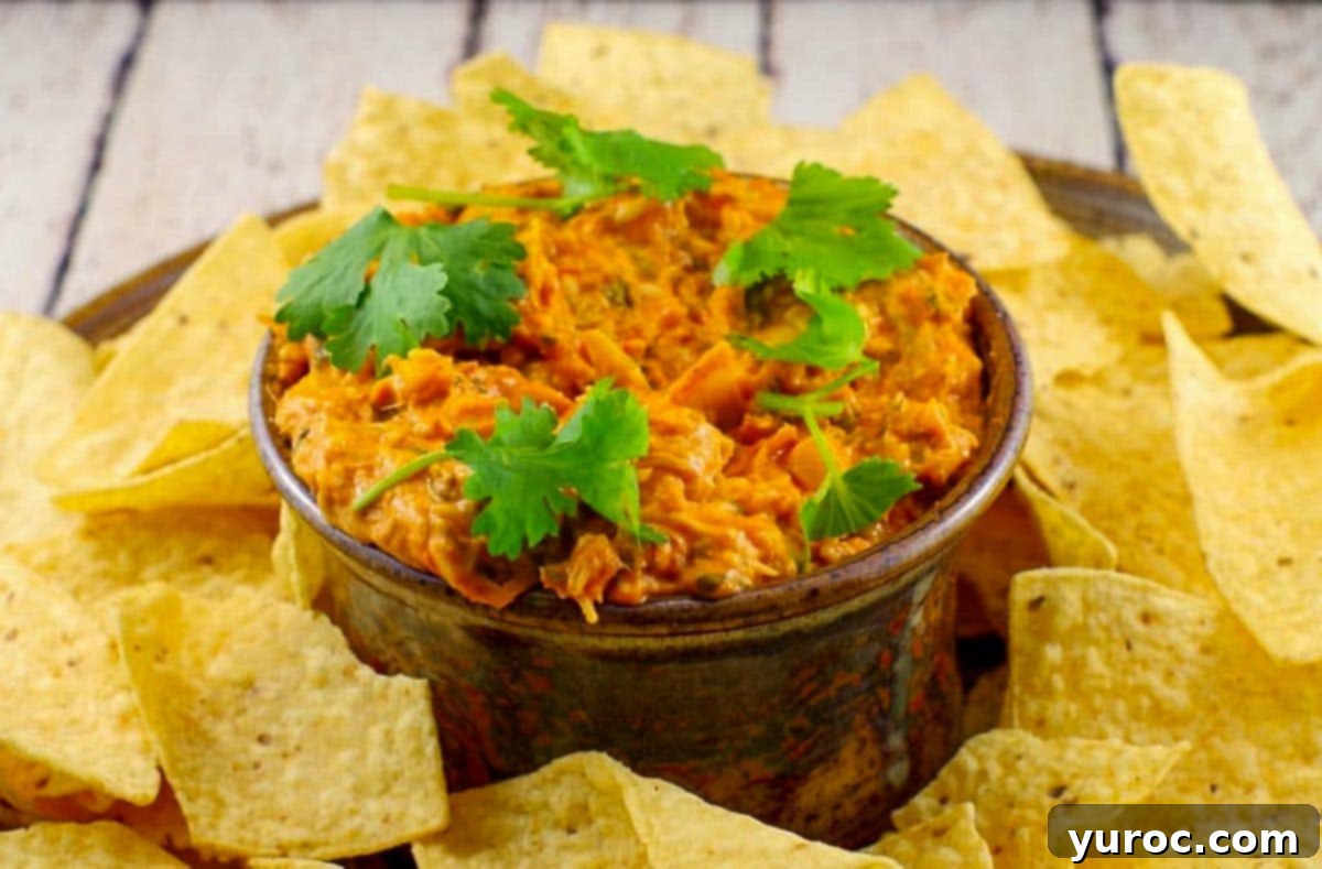 artichoke pizza dip in brown ceramic container with nachos surrounding it - Perfect for game day!