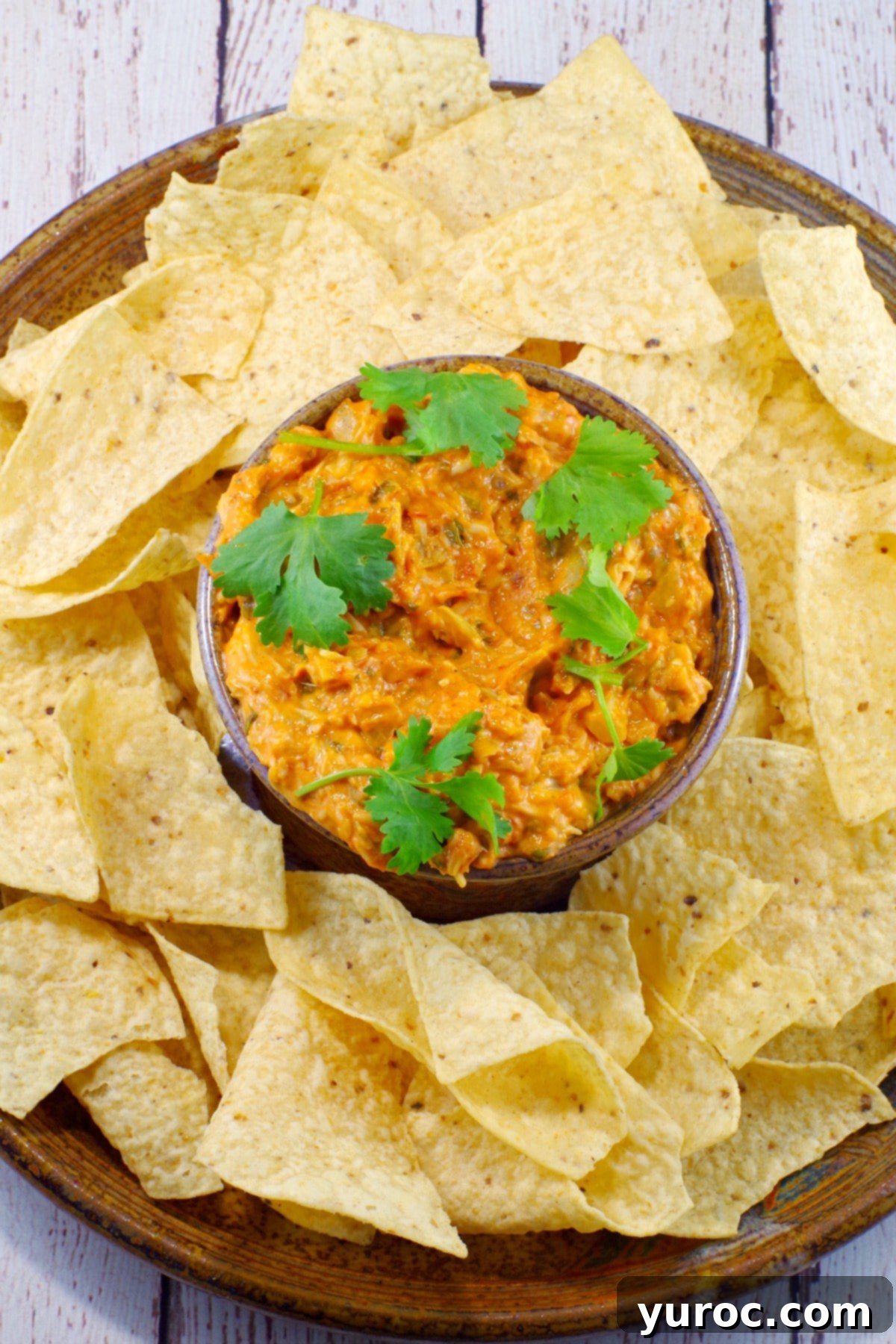 Hot artichoke pizza dip garnished with fresh cilantro, ready to be served at a party