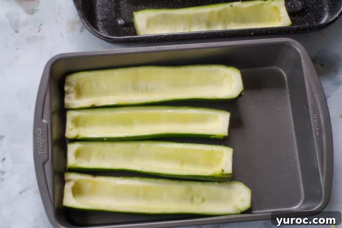 Hollowed out zucchini halves in baking dish.