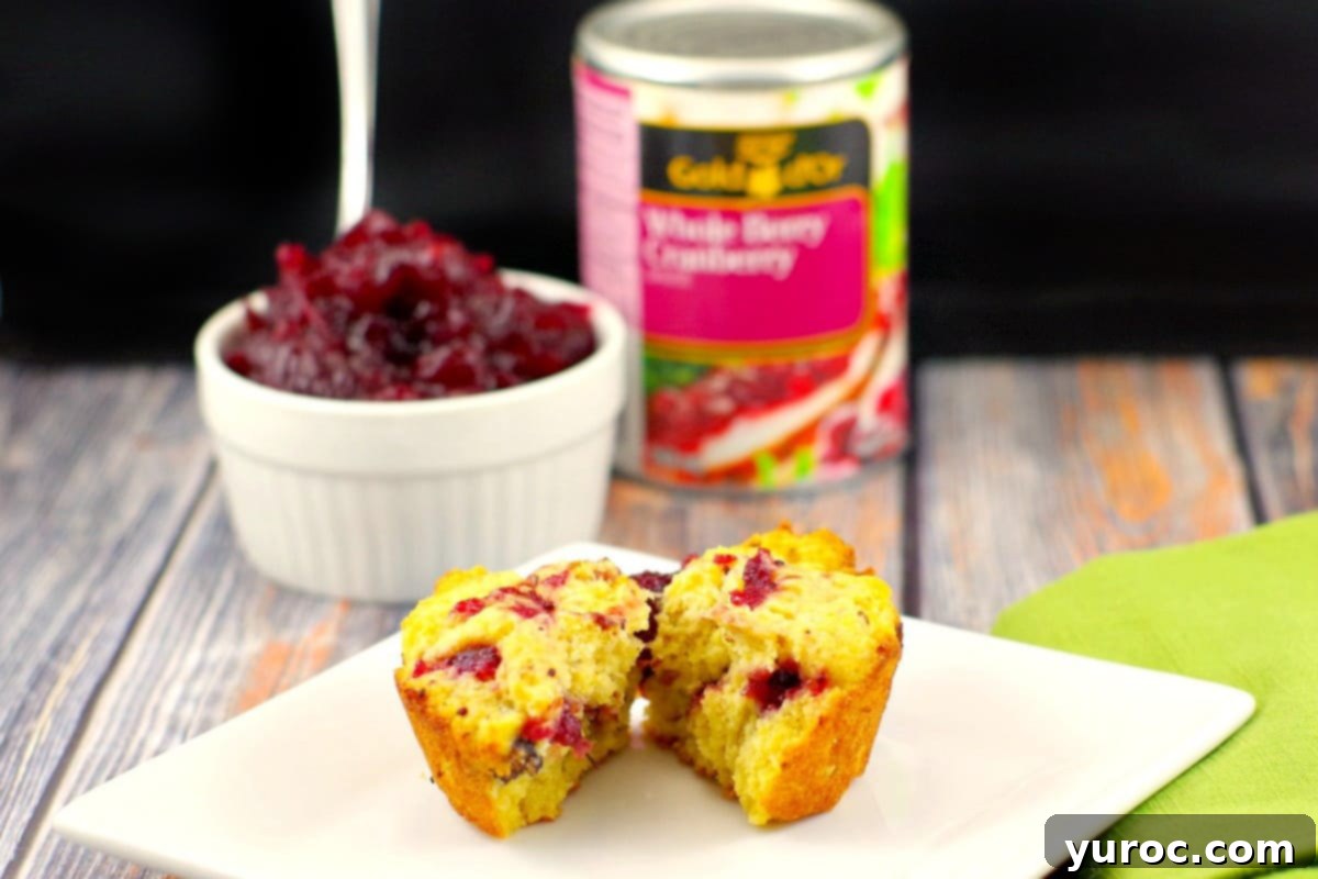cranberry cornbread muffin spilt in half with cranberry sauce and can in the background