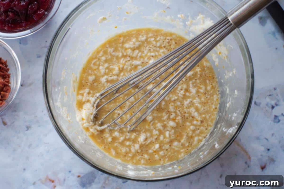 Shhortening and sugar in a glass bowl with a whisk and other wet ingredients added.