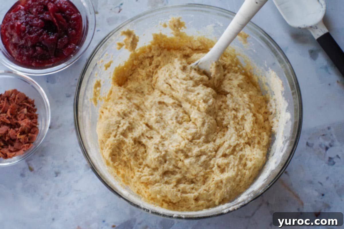 Wet and dry ingredients combined in a large glass bowl, with a silicone spoon.