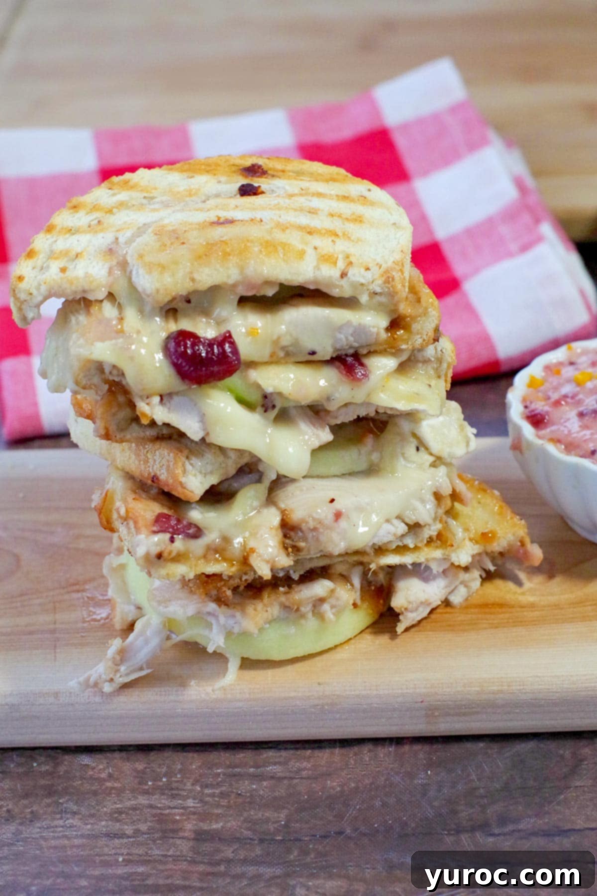Elevated Turkey Brie Panini 7 Leftover Turkey Panini stacked on a cutting board, with red checkered tea towel in the background