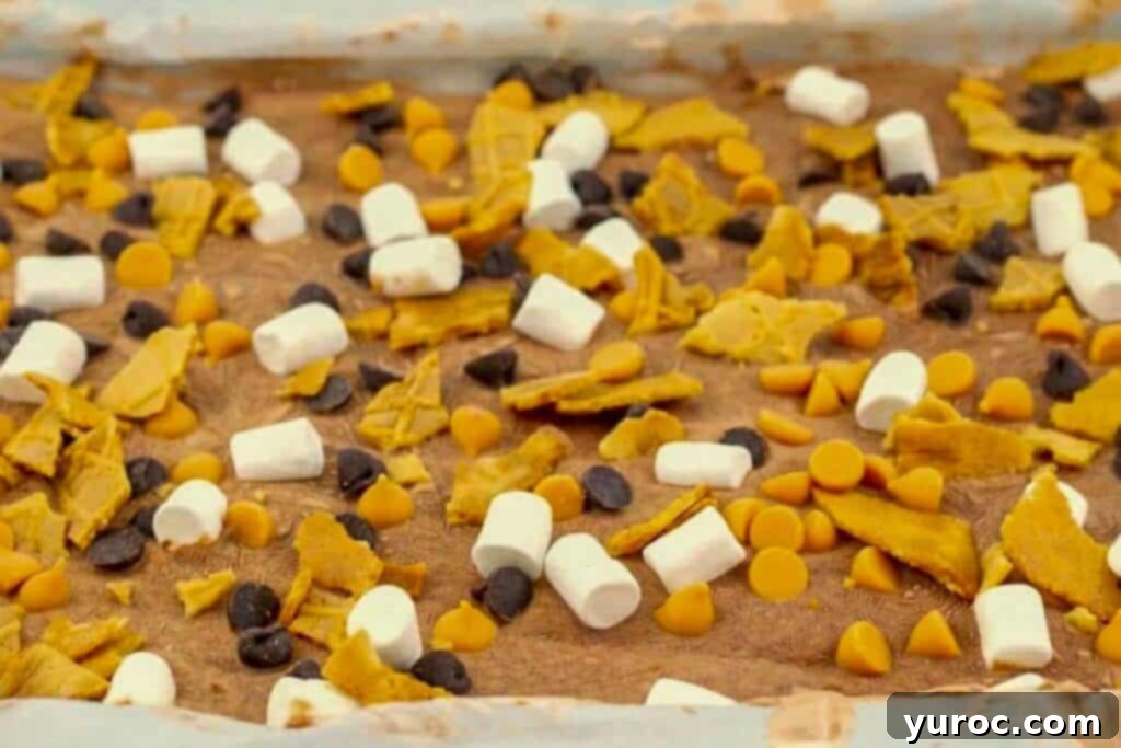 Rocky Road frozen Greek yogurt bark frozen on a parchment covered baking sheet, showing crunchy waffle cone pieces, mini marshmallows, and chocolate chips on a rich chocolate yogurt base.