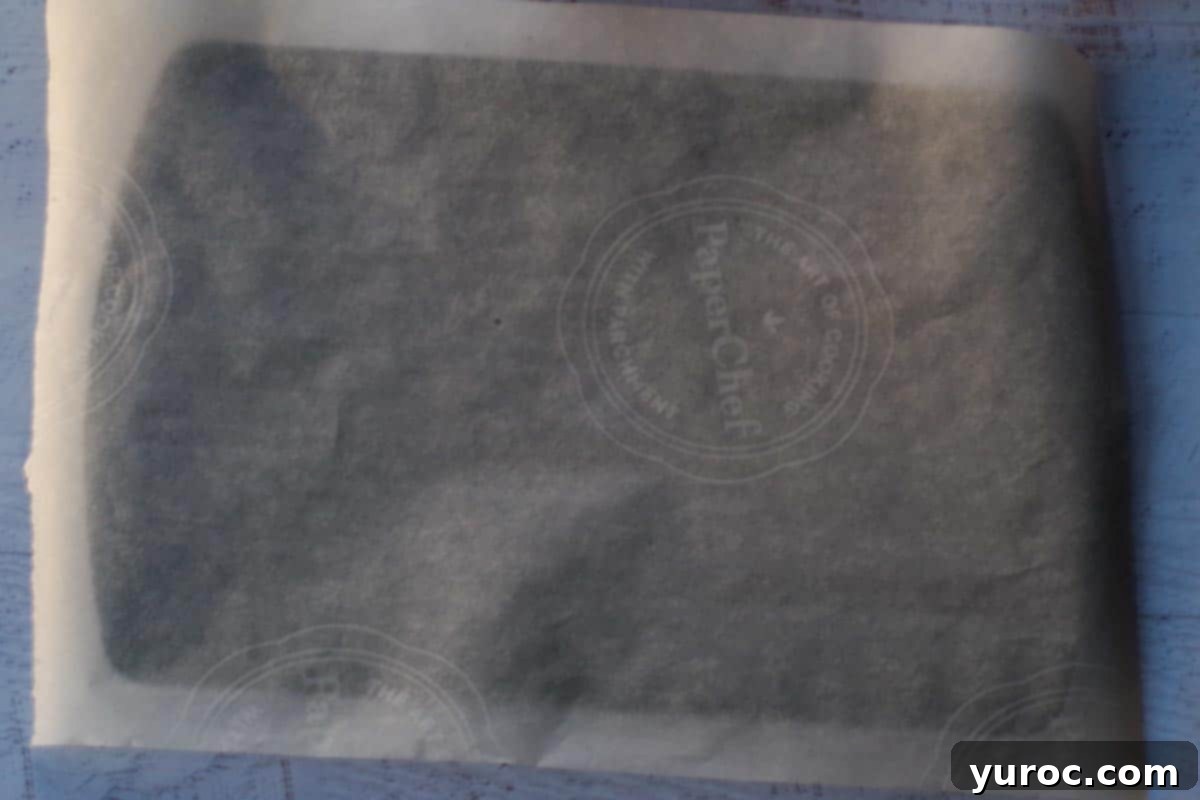 A pristine sheet of parchment paper laid flat on a metal baking sheet, ready for the yogurt mixture.